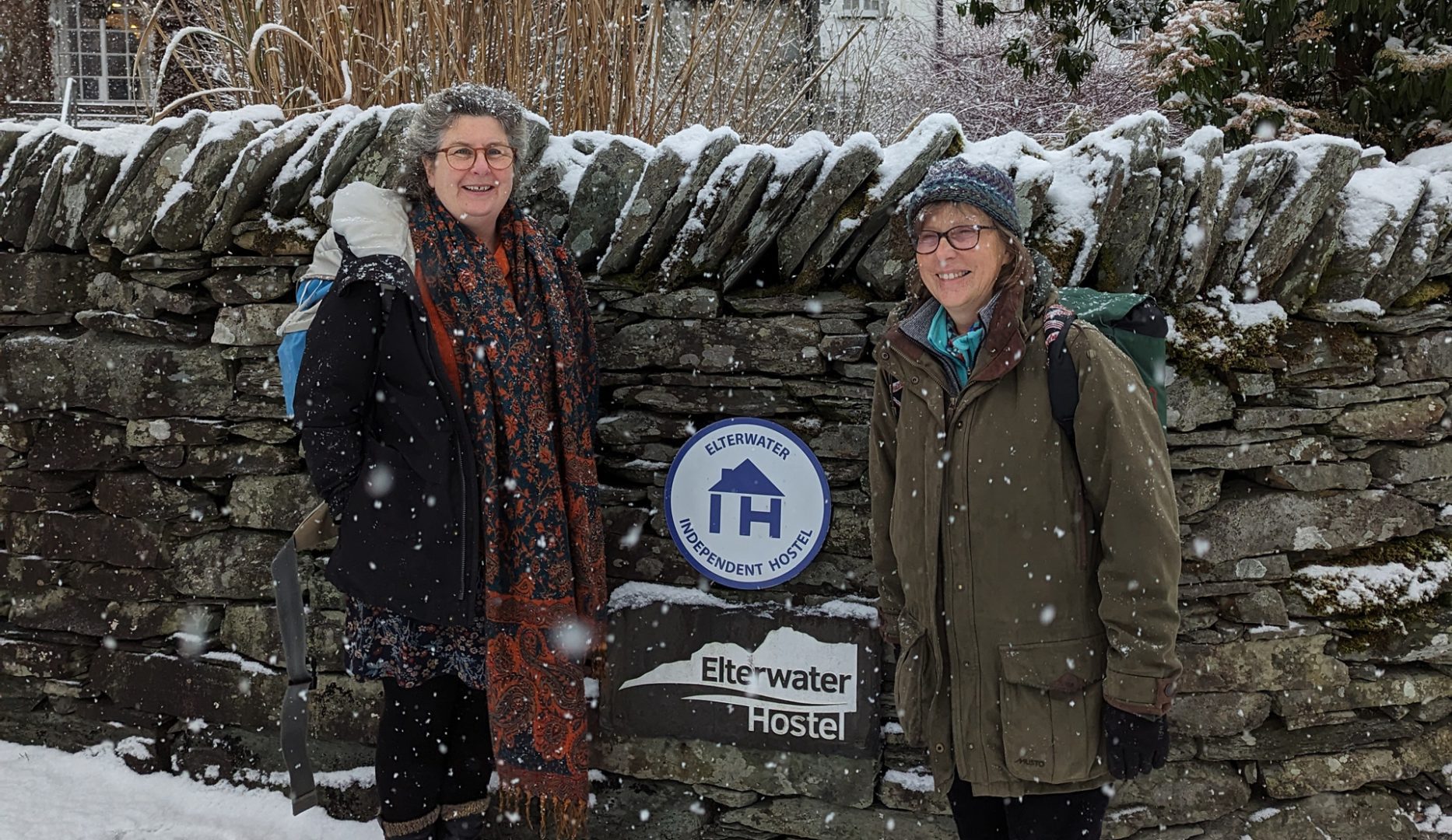 sam and penny outside elterwater hostel showing IHUK sign