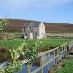 view of rousay hostel with fields in the forground