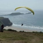 hang gliver over a beach near rhossili bunkhouse