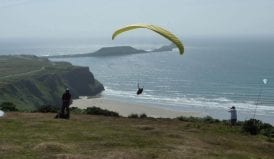 hang gliver over a beach near rhossili bunkhouse