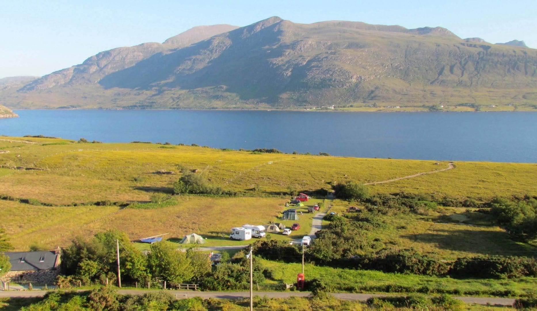 the bothy and campsite in the the foreground and the back ground is a beauiful loch and mountains. Perfect views for camping