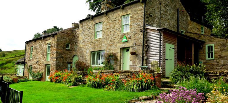 Ninebanks hostel, formerly part of the YHA looks breatiful with green window frames and a big lawn with lots of flowers