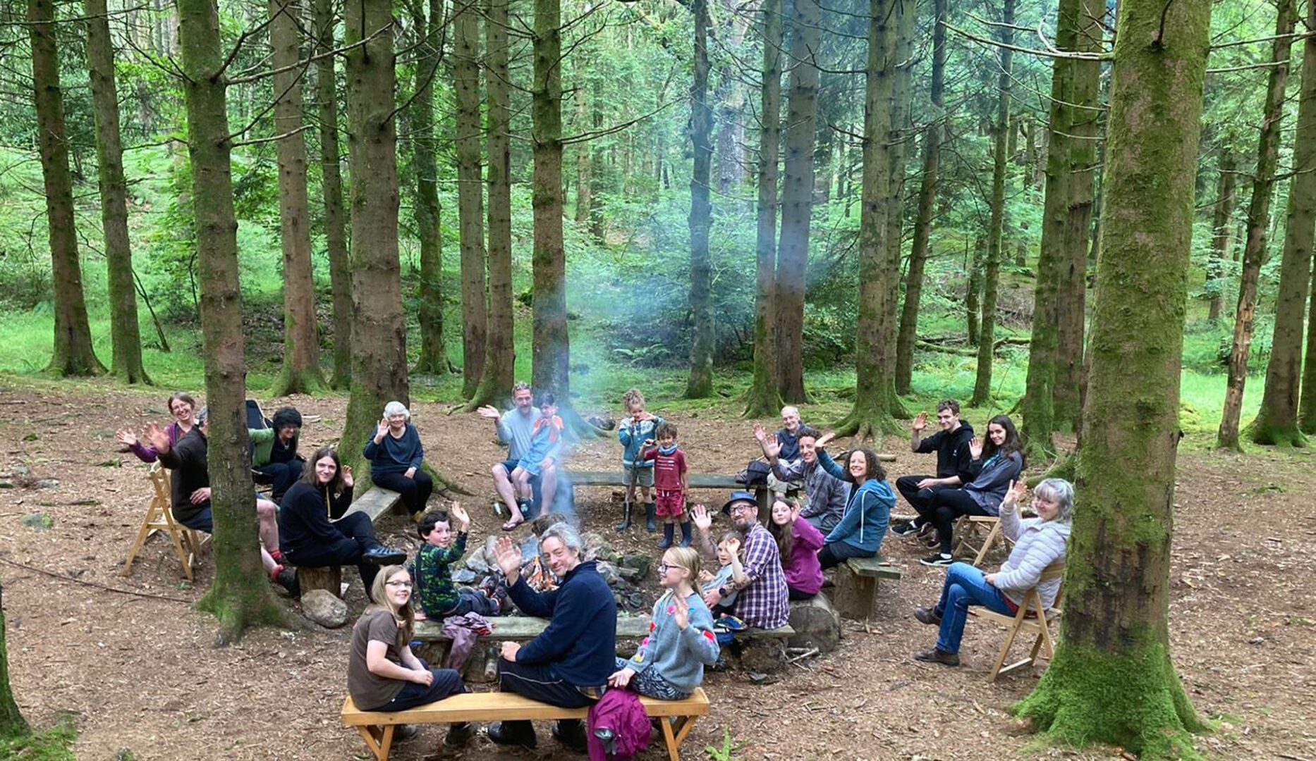 Woodland party of camping lots of people sat around the campfire in the forest