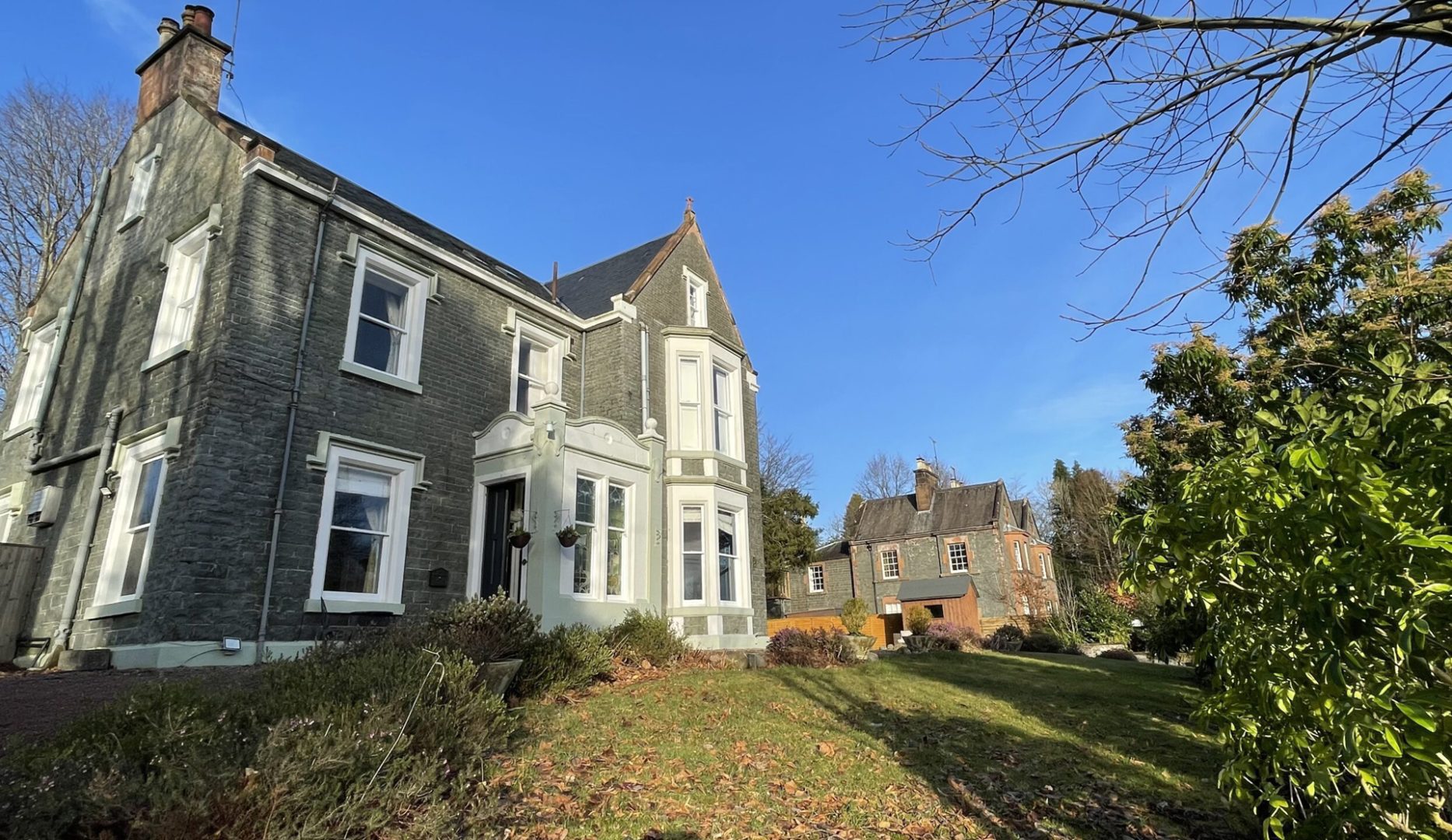 Exterior view of large grand house with neighbouring house in the distance