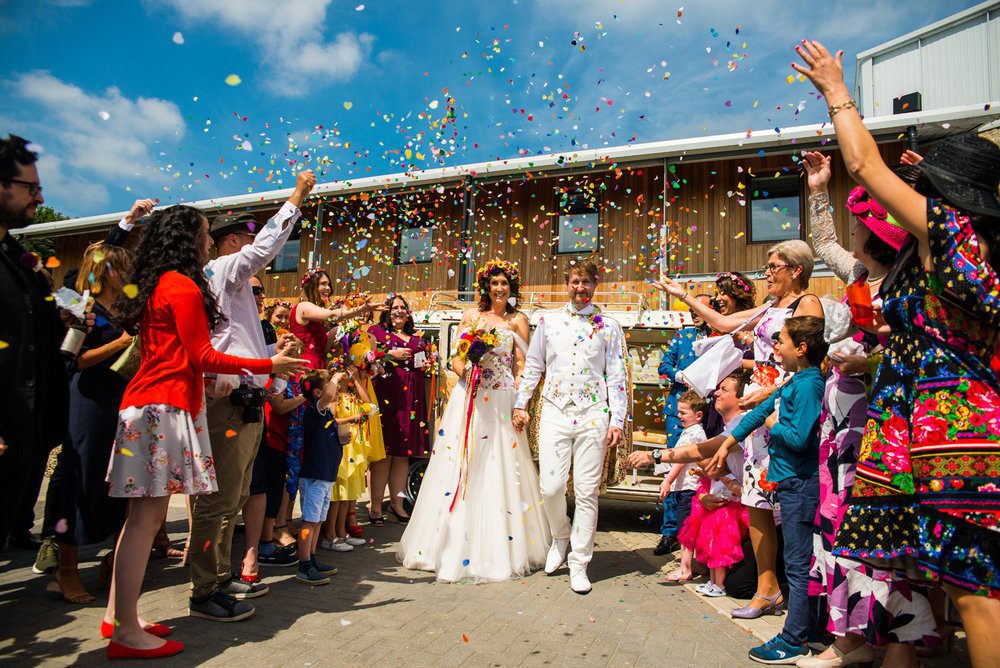 A bride and groom getting married and everyone is throwing confetti over them