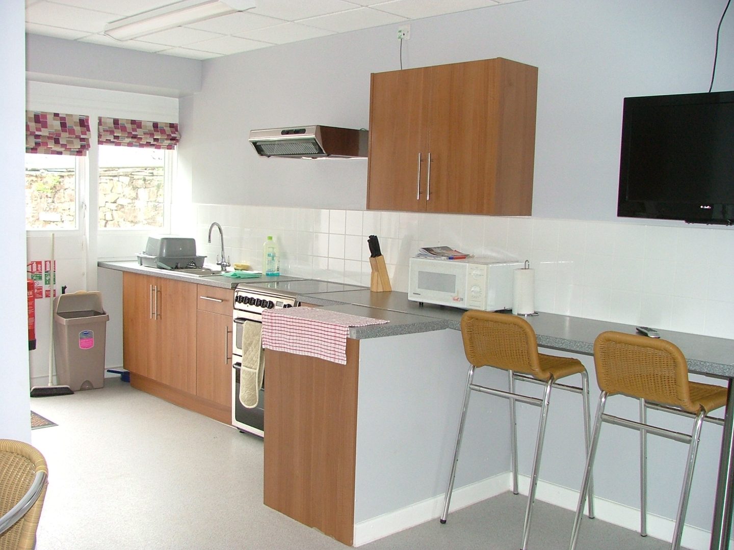 White floored kitchen, wooden cabinets and two chairs
