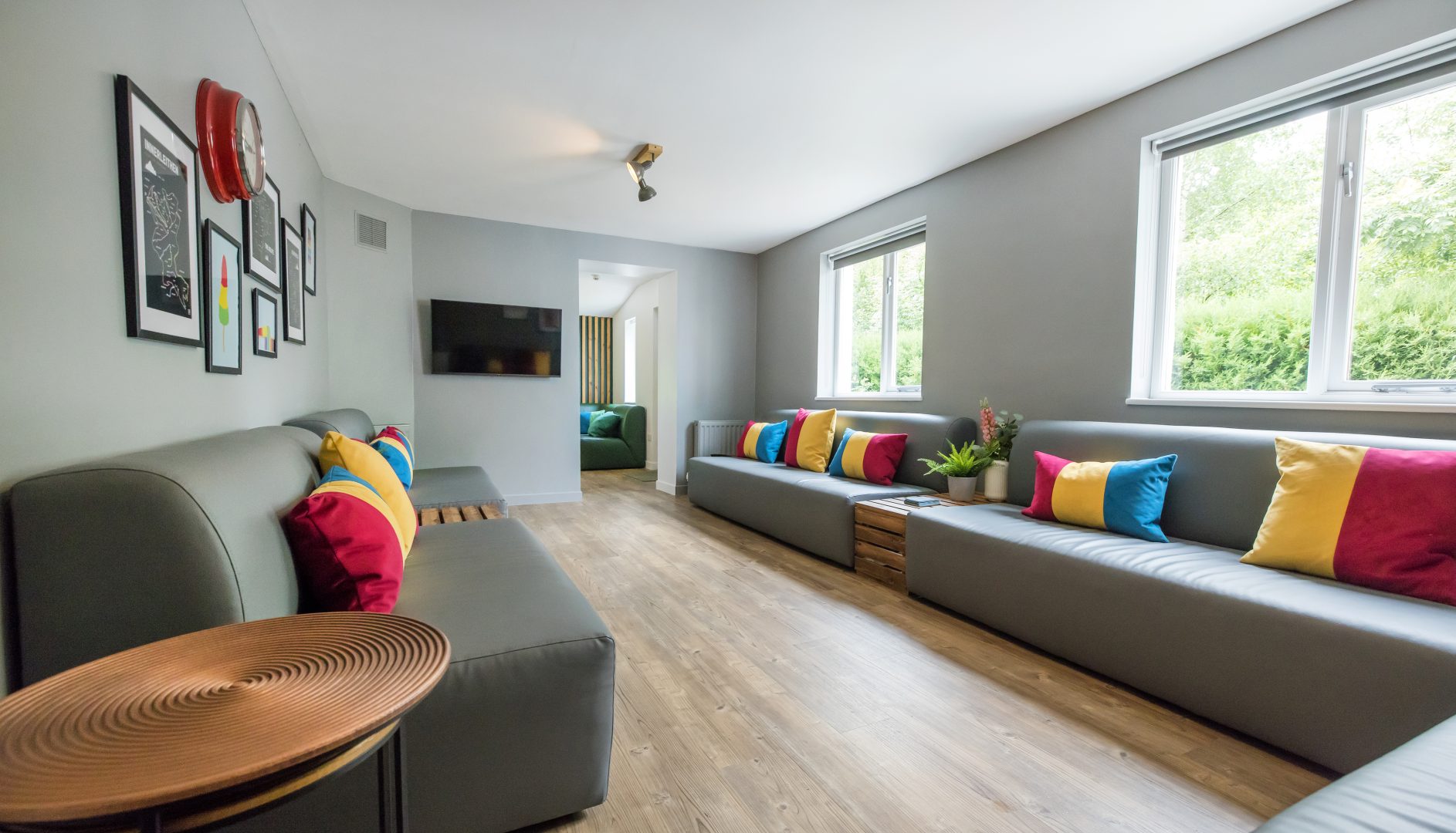 large lounge with super long grey sofas with brightly coloured cushions