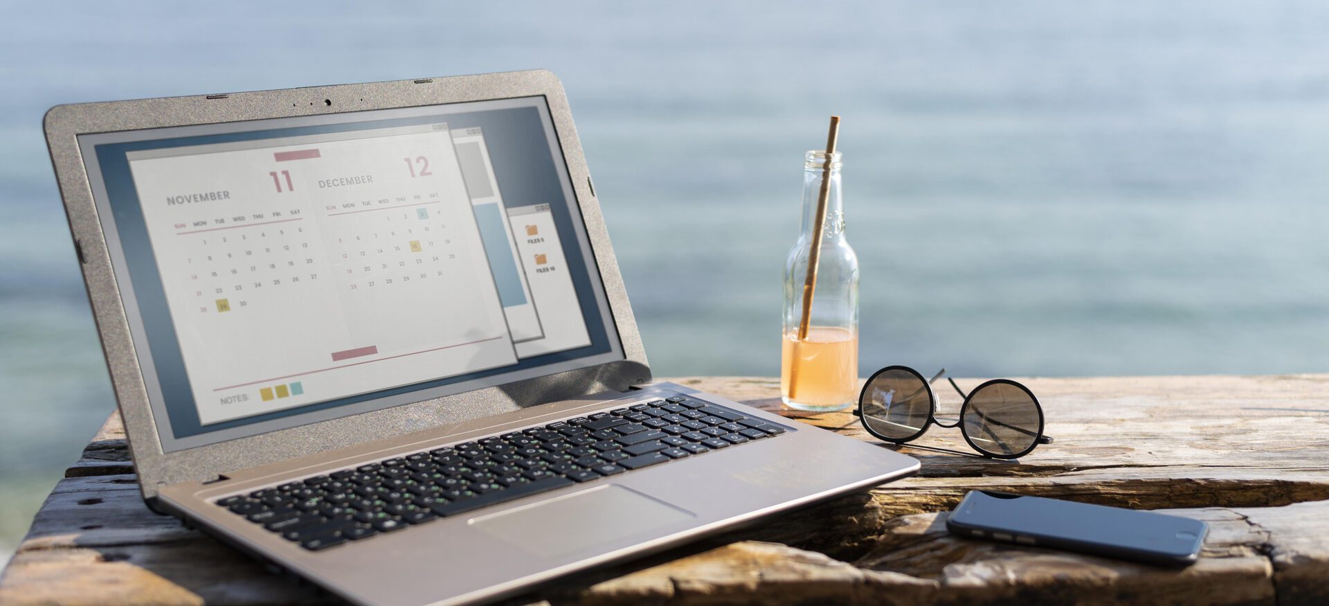 laptop showing an accommodation booking system and sun glases with a sea scene