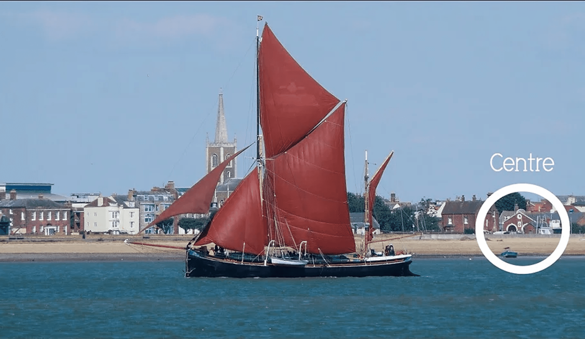 Yatch with red sails sailing in front of the centre
