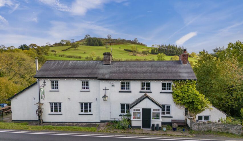 Front, (roadside) view of teh Dinas Castle Inn with a hill behind