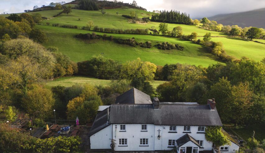 distance shot of the Dinas Castle Inn with the fields and hill behind