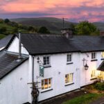 Exterior of Dinas Castle Inn with pink sunset behind