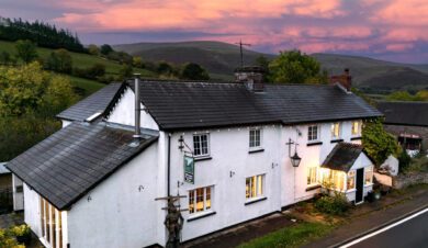 Exterior of Dinas Castle Inn with pink sunset behind