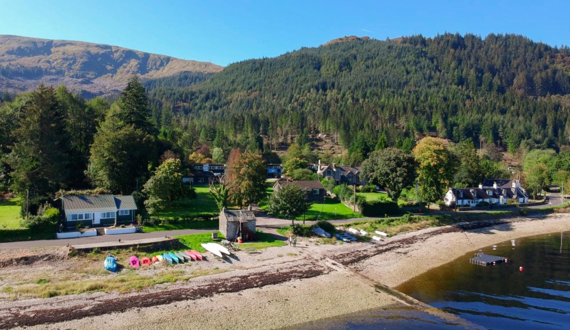 Aerial view of centre on the edge of Loch Long with mountains behind