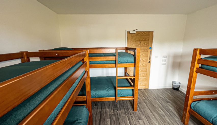 Dorm with sturdy wooden bunks and turquoise bed linen