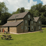 Exterior of stone former water mill in lawned area