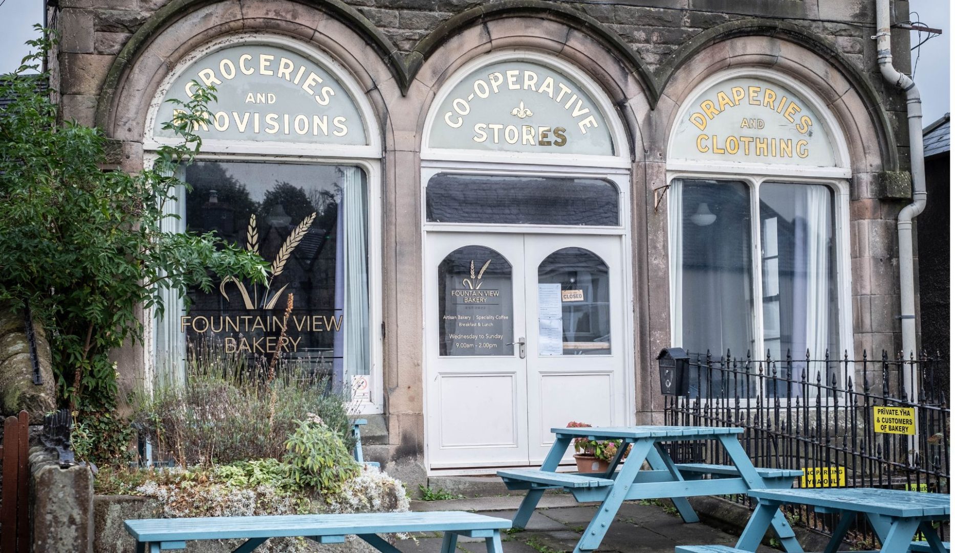 Exterior of hostel with blue picnic tables