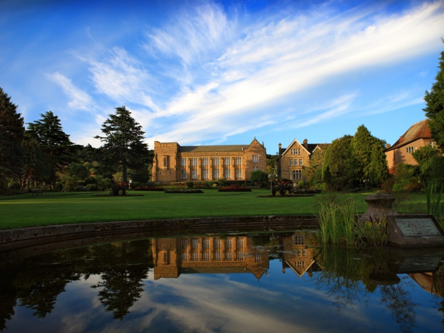 The school buildings with a lake and playing fields in the foreground