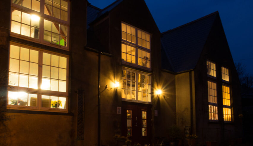 old school hostel trefin with the glow of the windows in the night