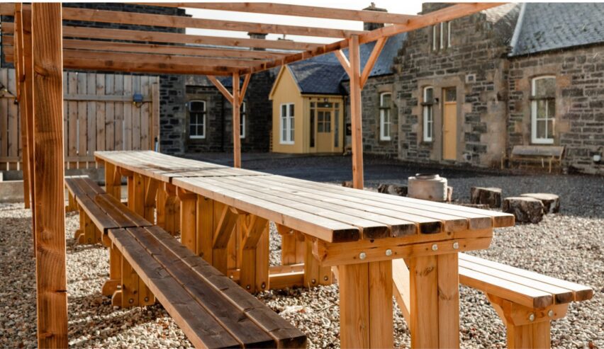 Long wooden pivnic benches under a pergola at Railway Rooma KIngussie