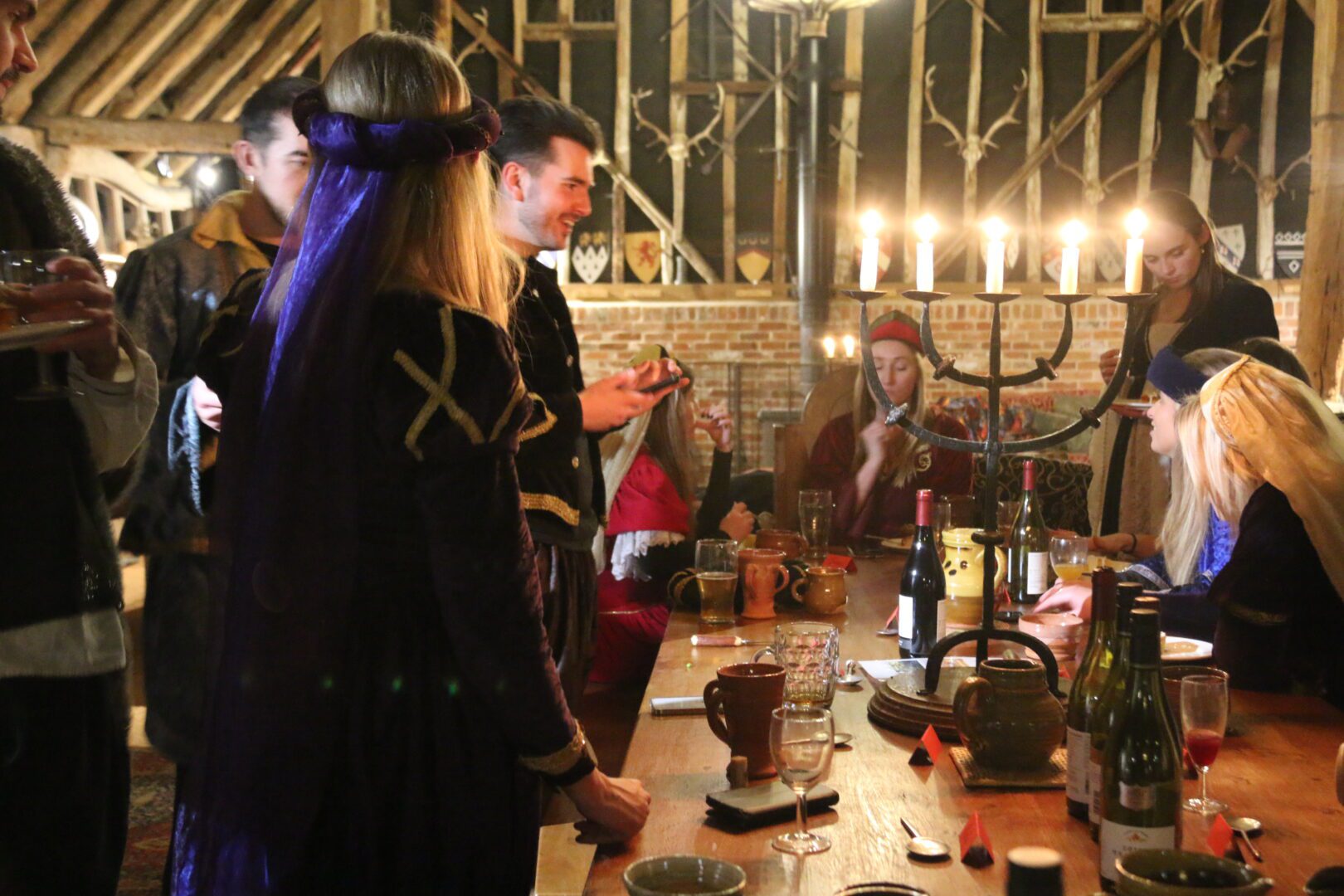 Christmas meal with wine and candals and young people in tudor costums at tudor barn