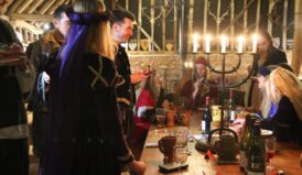 Christmas meal with wine and candals and young people in tudor costums at tudor barn