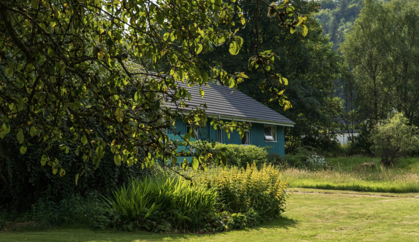 View of Inveraray Hostel in its wooded garden of early autumn