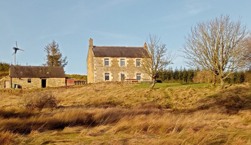 chartners farm hostel showing house on hill with autumn colours and wind turbine