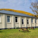 Helmsdale Lodge Youth Hostel showing picnic benches in the garden and yellow hillside behind