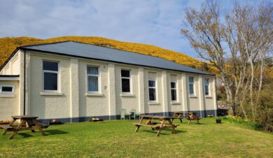 Helmsdale Lodge Youth Hostel showing picnic benches in the garden and yellow hillside behind