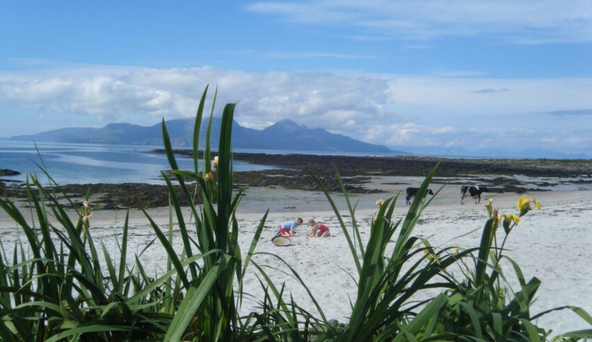 children playin in the sand at Gallanach Bay on isle of much scottish island