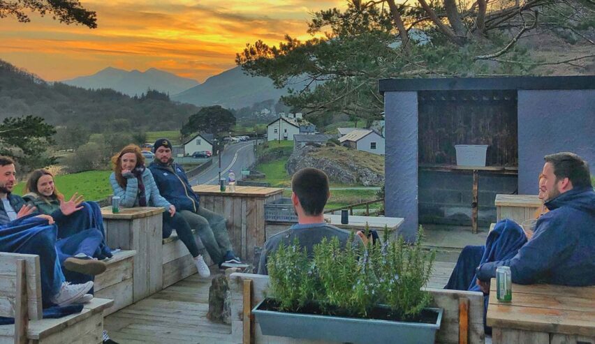 hikers enjoying te view of mountains from the pation of rocks at plas curig