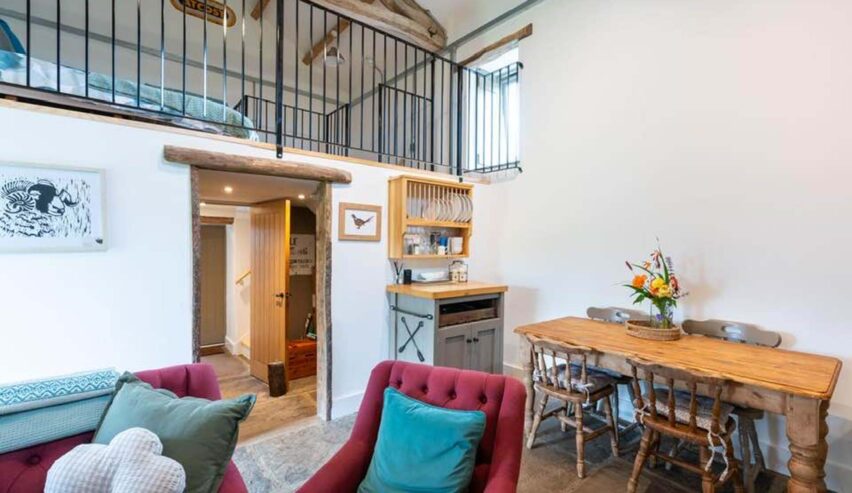inside Aysgill camping barn showing comfy sofas table with flowers and masinin sleeping area
