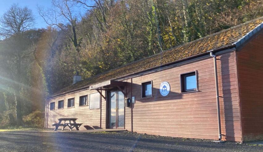 external view of the shed bunkhouse on the antrim coast of northern ireland with winter sunshine on the wood behind it and independent hostel sign on the front