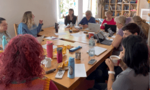 Group of people sat around a large table with laptops and notebooks