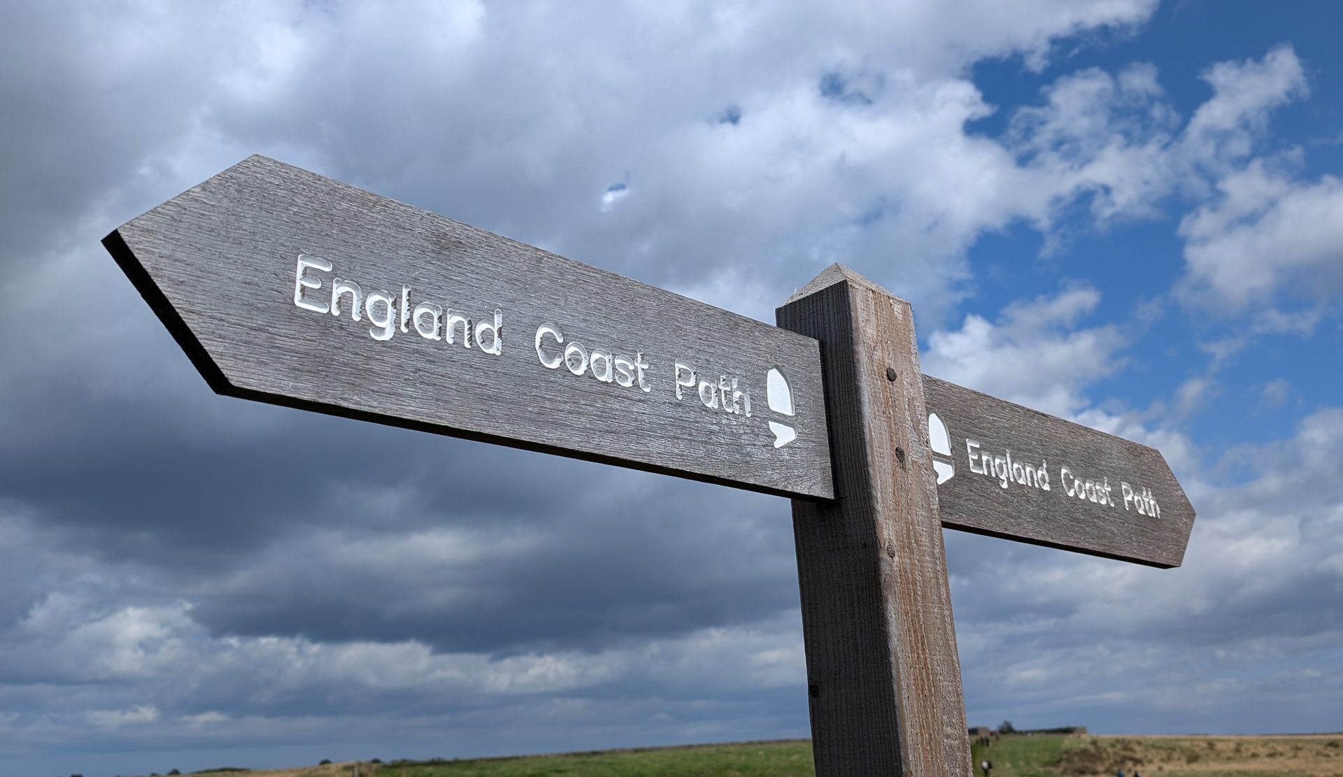 Sign for the England Coast Path against a stormy sky
