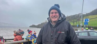 man in bobble hat and warm suit after wild siming in the sea
