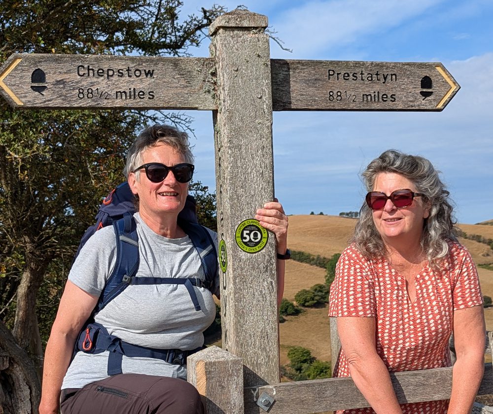 two walkers by a sign showing the halfway point on offas dyke