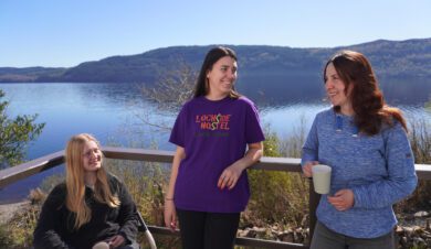 backpackers at Lochside Hostel with a view of lochness behind them